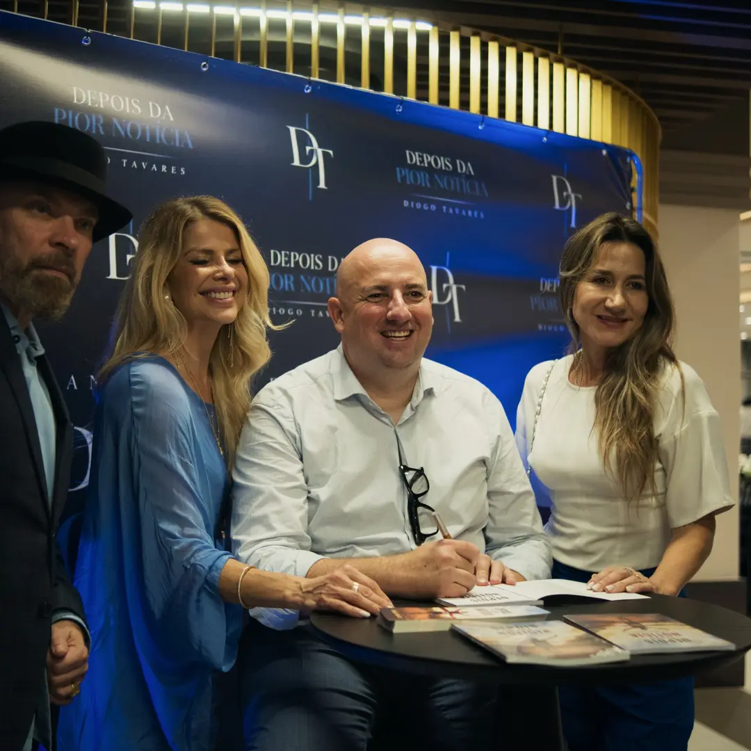 Autor autografando exemplares no lançamento de Depois da Pior Notícia, cercado por convidados